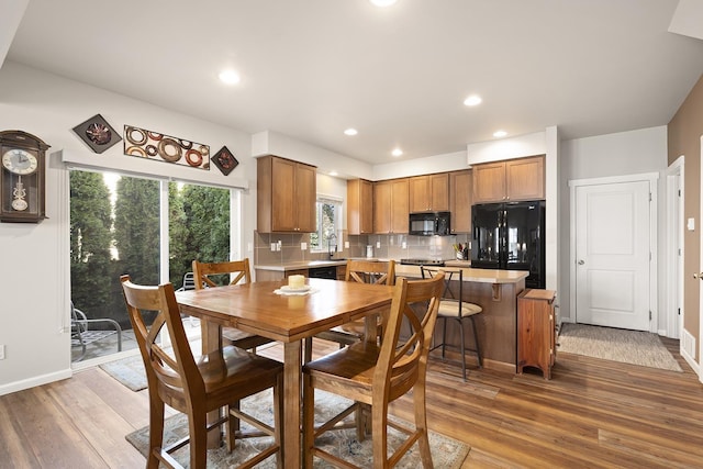 dining space featuring baseboards, wood finished floors, and recessed lighting