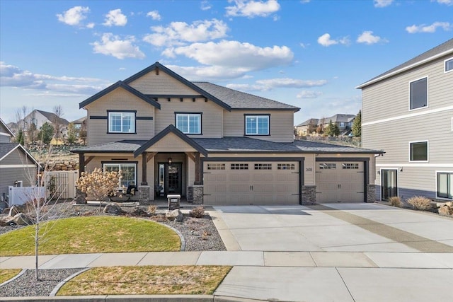 craftsman-style home featuring a garage, stone siding, fence, and concrete driveway