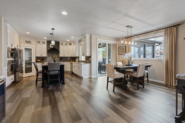 dining area with recessed lighting, dark wood-style flooring, a textured ceiling, and baseboards