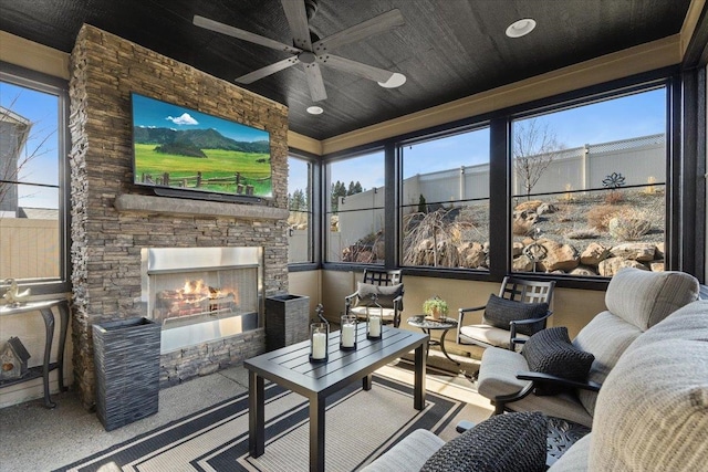 sunroom / solarium with an outdoor stone fireplace, a wealth of natural light, and a ceiling fan