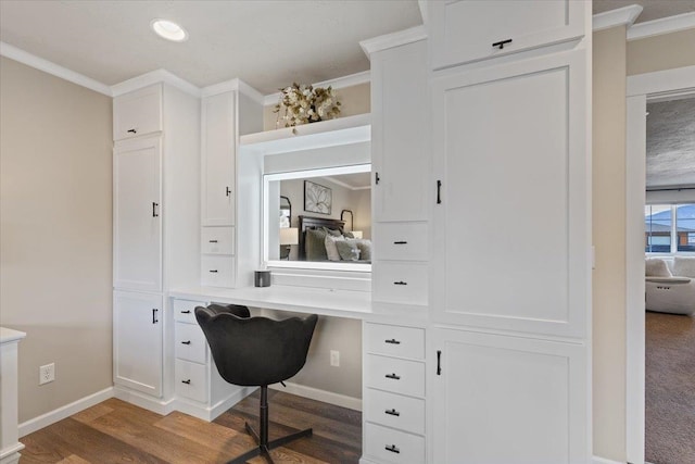 home office with crown molding, baseboards, built in desk, and wood finished floors