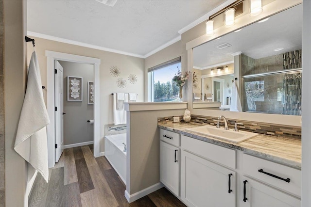 full bath with a garden tub, wood finished floors, vanity, a stall shower, and crown molding