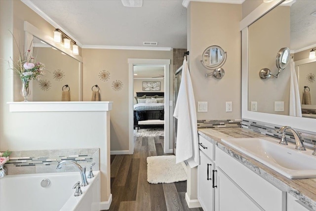 bathroom featuring visible vents, wood finished floors, ensuite bathroom, a garden tub, and vanity