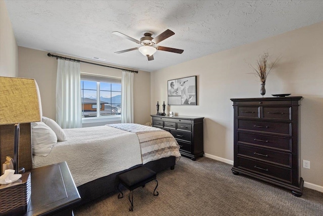 bedroom featuring dark colored carpet, visible vents, a textured ceiling, and baseboards