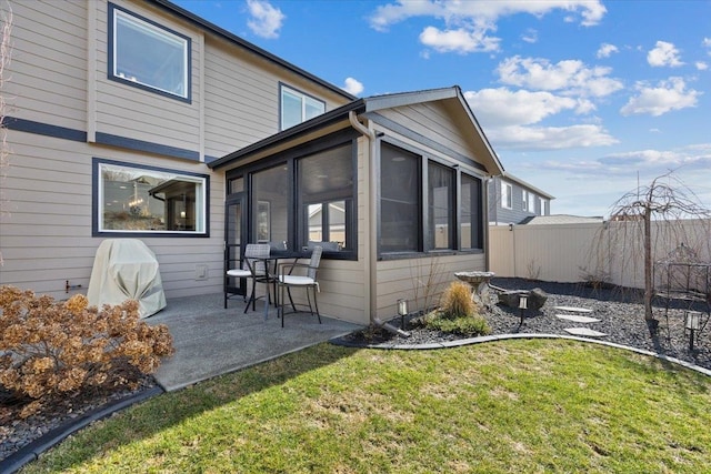 view of home's exterior with a sunroom, fence, a lawn, and a patio