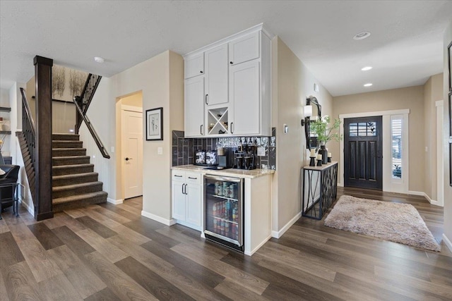 kitchen with dark wood-style flooring, decorative backsplash, white cabinetry, beverage cooler, and baseboards