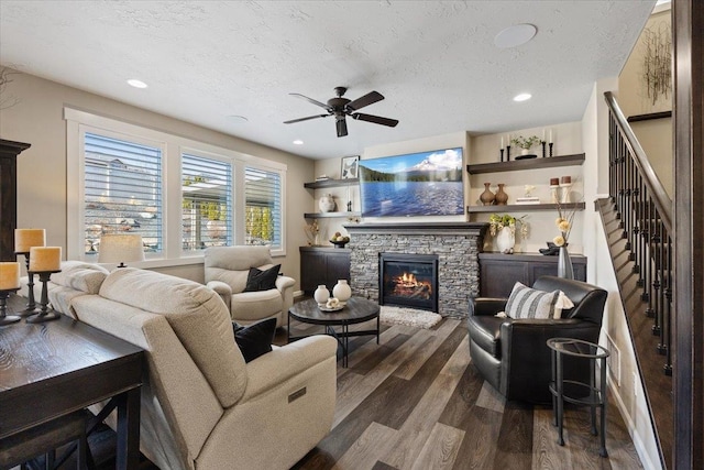 living room with a textured ceiling, stairs, a fireplace, and dark wood-type flooring