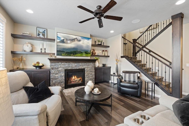 living area with a stone fireplace, recessed lighting, wood finished floors, a ceiling fan, and stairs