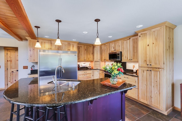 kitchen featuring appliances with stainless steel finishes, light brown cabinets, a sink, and a kitchen breakfast bar