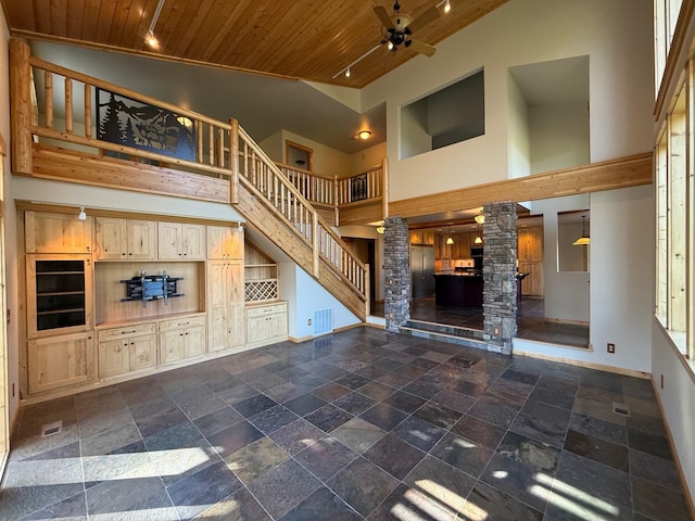 unfurnished living room with decorative columns, stairway, high vaulted ceiling, wooden ceiling, and a ceiling fan
