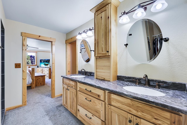 bathroom featuring ensuite bathroom, double vanity, a sink, and baseboards