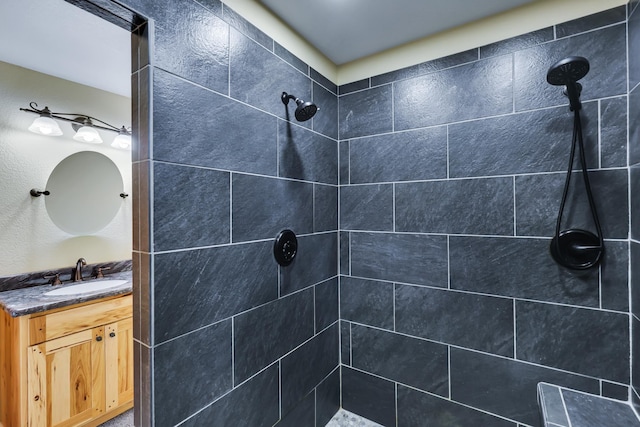 bathroom with a tile shower and vanity