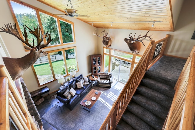 living area with a ceiling fan, high vaulted ceiling, wooden ceiling, baseboards, and stairs