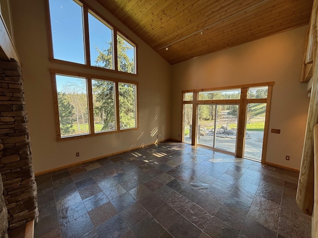 spare room with baseboards, wood ceiling, stone tile flooring, and high vaulted ceiling