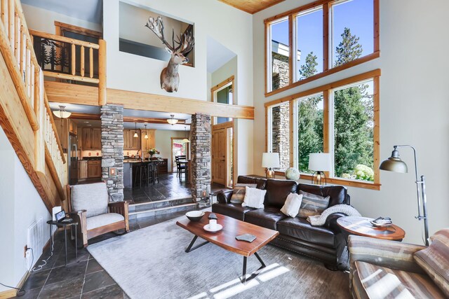 living room with stone tile flooring, a towering ceiling, and decorative columns