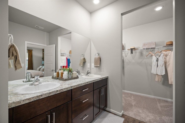 full bathroom featuring double vanity, a spacious closet, visible vents, and a sink