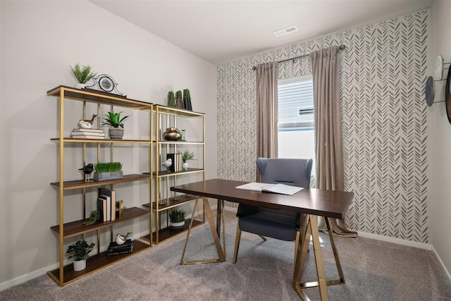 carpeted home office with an accent wall, visible vents, and baseboards