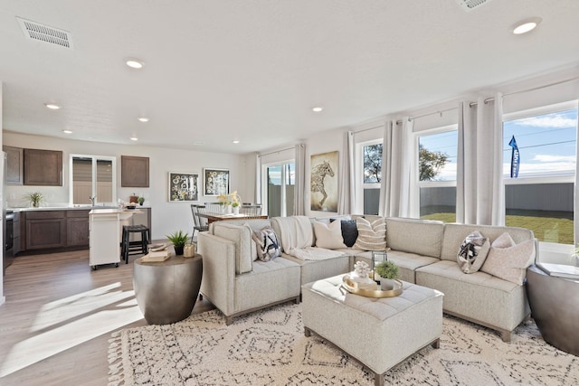 living room with recessed lighting, visible vents, and light wood-style flooring