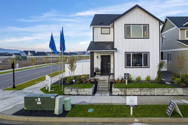 modern farmhouse style home with board and batten siding, a shingled roof, and fence