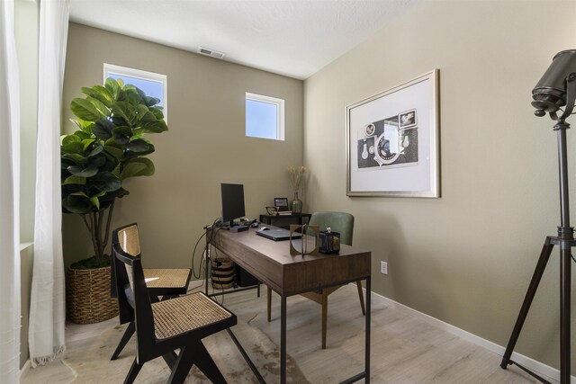 office space featuring light wood-style flooring, visible vents, and baseboards