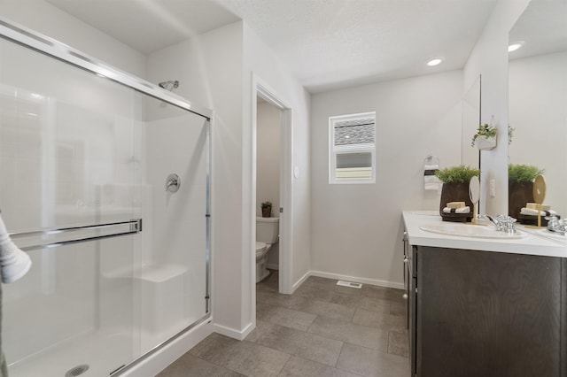 bathroom featuring toilet, a shower stall, vanity, and baseboards