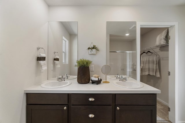 full bath with double vanity, a stall shower, and a sink