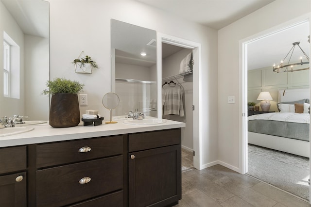 ensuite bathroom with connected bathroom, a sink, a shower stall, double vanity, and an inviting chandelier