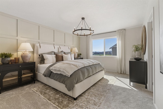 bedroom featuring light carpet, a chandelier, a decorative wall, and a textured ceiling