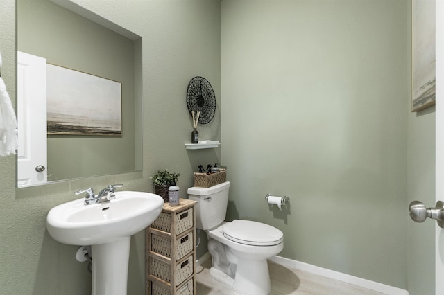 half bath with a sink, toilet, and baseboards