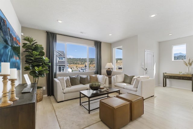 living area with light wood-style flooring, visible vents, baseboards, and recessed lighting