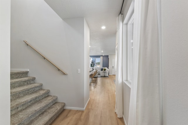 staircase featuring baseboards, wood finished floors, and recessed lighting