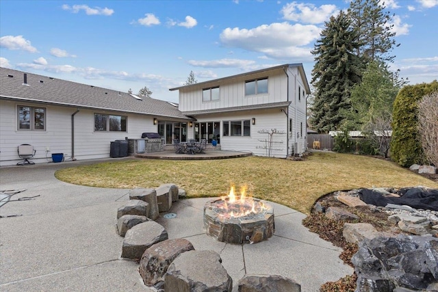 back of property featuring an outdoor fire pit, a patio, fence, a yard, and board and batten siding