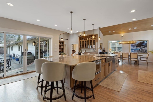 kitchen with a spacious island, plenty of natural light, light wood finished floors, and light stone countertops