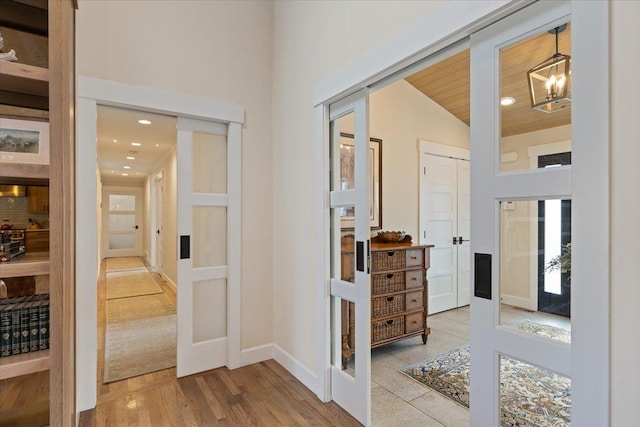 hallway with a chandelier, recessed lighting, wood finished floors, baseboards, and french doors