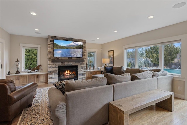 living room with baseboards, recessed lighting, a fireplace, and light wood-style floors