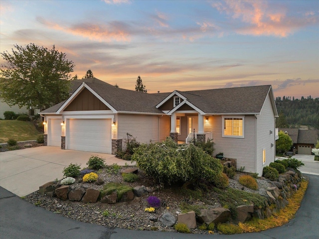 711 W Bolan Ave, Spokane, WA 99224 - view of front of property featuring an attached garage, concrete driveway, board and batten siding, stone siding, and roof with shingles
