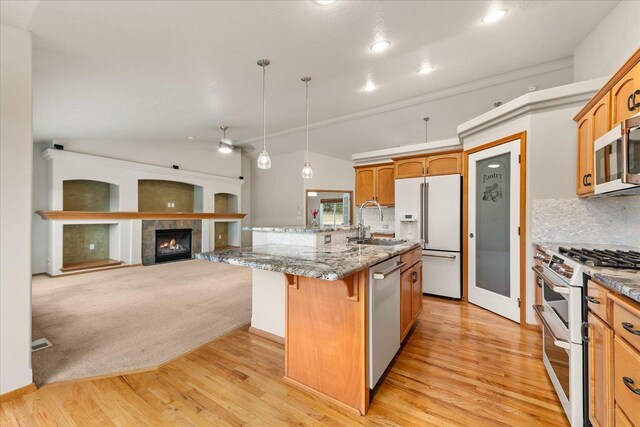 711 W Bolan Ave, Spokane, WA 99224 - kitchen featuring stainless steel appliances, a breakfast bar, light wood-style flooring, tasteful backsplash, and vaulted ceiling