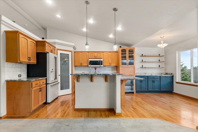 711 W Bolan Ave, Spokane, WA 99224 - kitchen with white fridge with ice dispenser, a kitchen bar, tasteful backsplash, dark stone countertops, and decorative light fixtures
