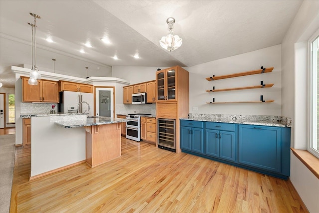711 W Bolan Ave, Spokane, WA 99224 - kitchen featuring wine cooler, appliances with stainless steel finishes, vaulted ceiling, decorative backsplash, and light wood-style floors