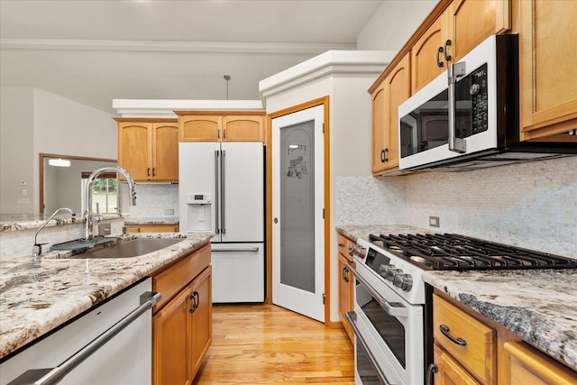 711 W Bolan Ave, Spokane, WA 99224 - kitchen with white appliances, a sink, light wood-style flooring, light stone countertops, and backsplash