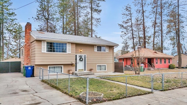 split foyer home featuring a fenced front yard, a front yard, a gate, and a chimney