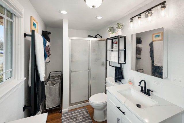 bathroom featuring vanity, wood finished floors, a shower stall, and toilet