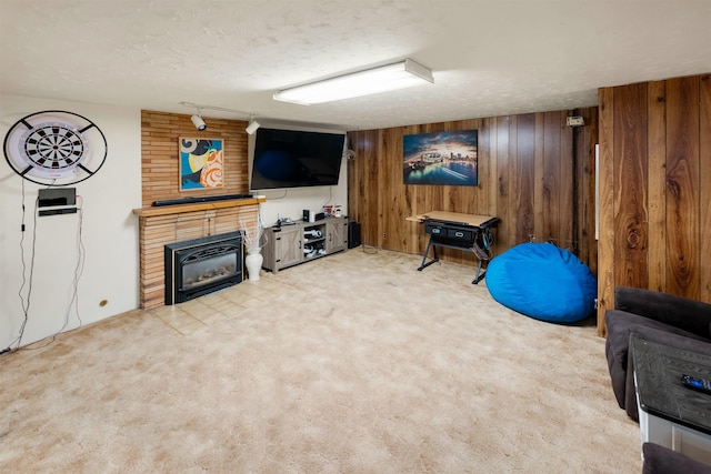 interior space featuring a textured ceiling, wooden walls, light colored carpet, a glass covered fireplace, and track lighting