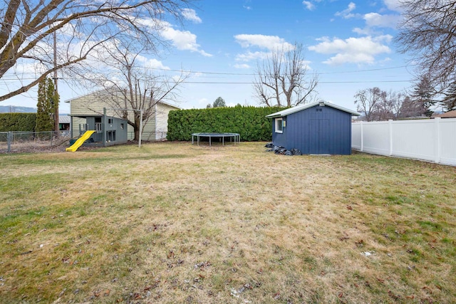 view of yard featuring an outbuilding, a storage shed, a trampoline, and a fenced backyard