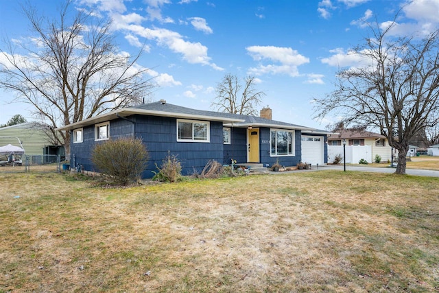 ranch-style house with a garage, driveway, a chimney, fence, and a front yard