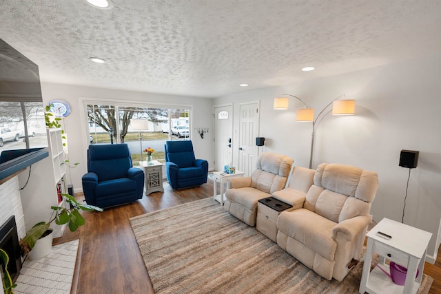 living room featuring a fireplace with flush hearth, a textured ceiling, wood finished floors, and recessed lighting