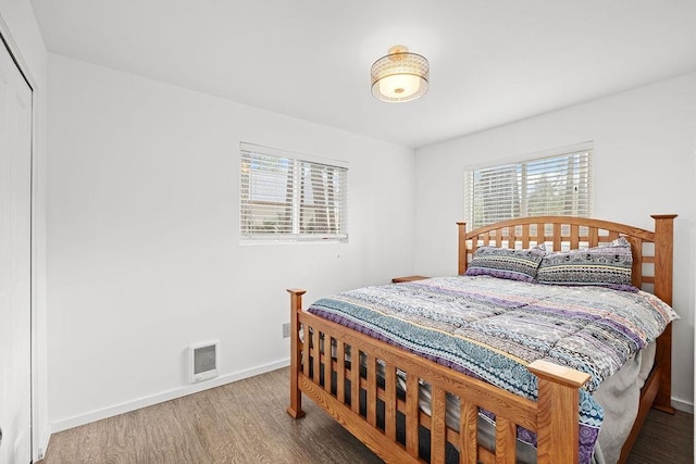 bedroom with wood finished floors, visible vents, baseboards, and multiple windows