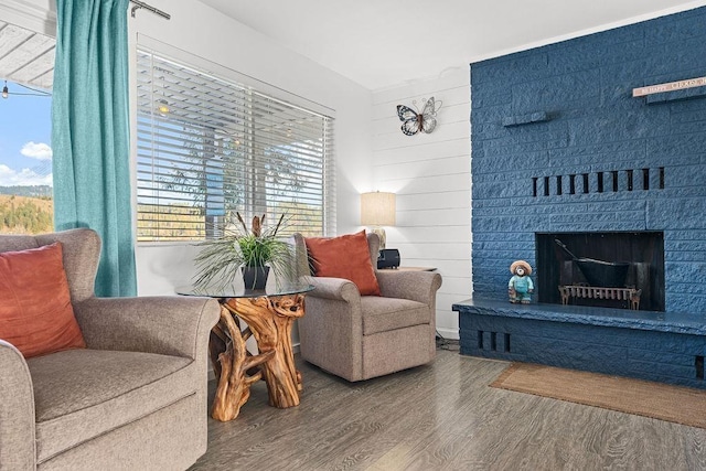 sitting room with a fireplace with raised hearth and wood finished floors