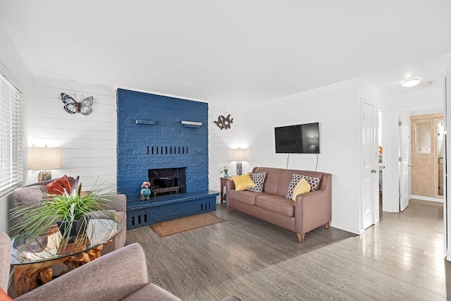 living room with a fireplace, baseboards, and wood finished floors