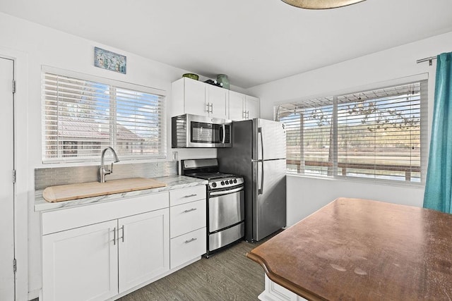 kitchen with dark wood-style floors, stainless steel appliances, a sink, and white cabinetry